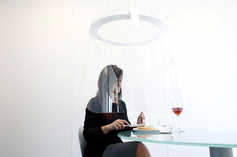 A woman poses under a Plex'Eat prototype plexiglas bubble by designer Christophe Gernigon, which surrounds diners to protect them from the coronavirus, during a presentation in Cormeilles-en-Parisis, near Paris, as restaurants in France prepare to re-open post-lockdown. REUTERS/Benoit Tessier